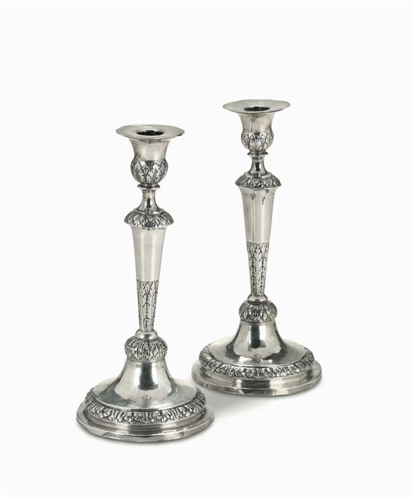 A pair of candlesticks in molten, embossed and chiselled silver. Genoa, late 19th century, city guarantee mark - coiled dolphin - and great works stamp for II° title silver - crowned St. Mauritius cross - stamps in use from 1825 to 1872