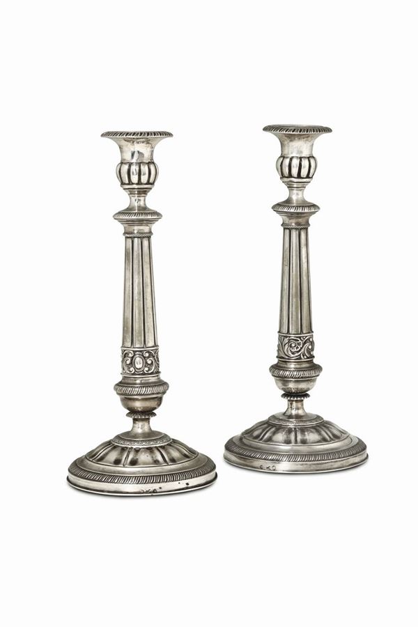 A pair of candle holders in molten, embossed and chiselled silver, Milan, half of the 19th century, guarantee marks (plough and globe with zodiac and seven Trions) and mark for silversmith Francesco Ceppi (…1855 – 1856…).