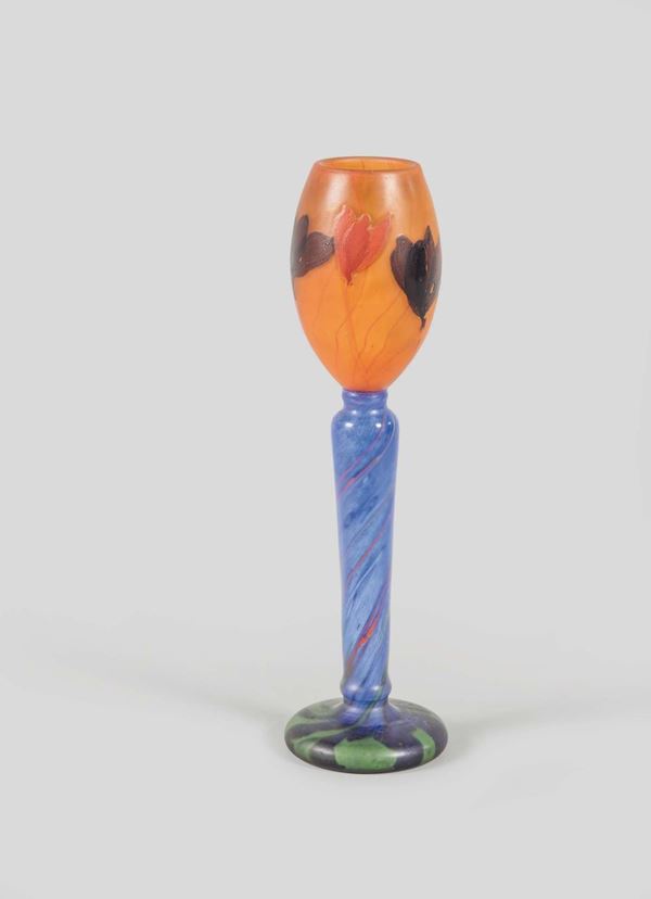 Emilié Gallé, France, 1900 ca. An important vase in orange glass paste with a marquetry decor of flowers, grindstone polished, on a tall blue glass stem with a decor of polychrome threads