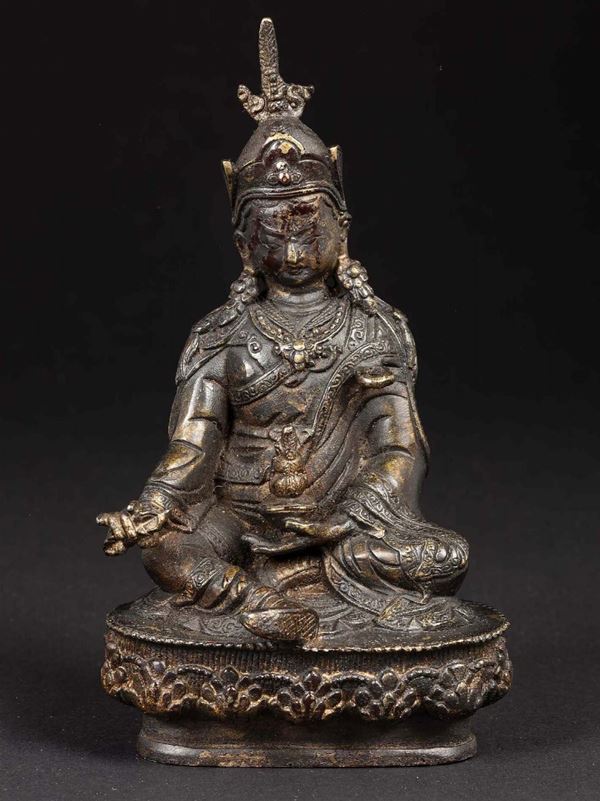 A semi-gilt bronze figure of a warrior seated on a lotus flower, Tibet, 18th century