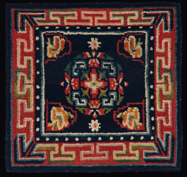 A meditation mat with a central medallion on a blue backdrop and a meander frame, Tibet, 19th century
