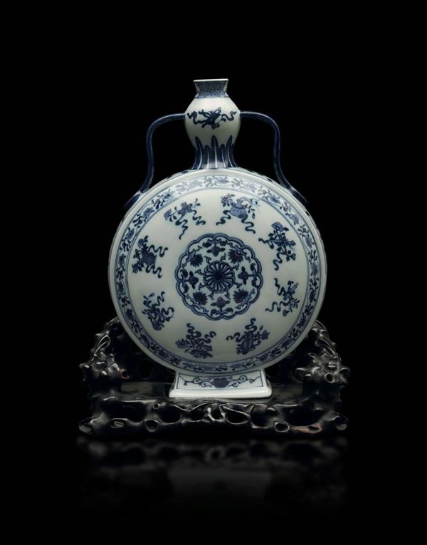 A blue and white porcelain flask with a central medallion and botanical decors on a carved wooden base, China, 20th century