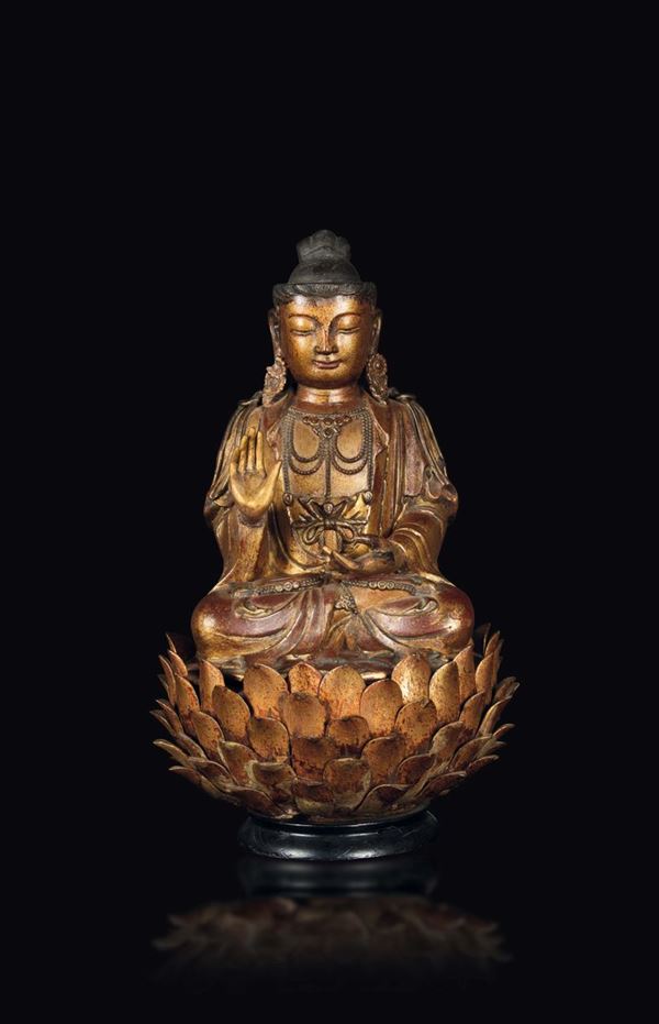 A lacquered and gilded wood Buddha figure seated on a lotus flower, China, Ming Dynasty, half of the  [..]