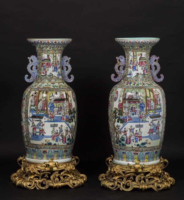 Coppia di grandi vasi in porcellana Canton con scene di vita quotidiana entro riserve su basi in bronzo  [..]