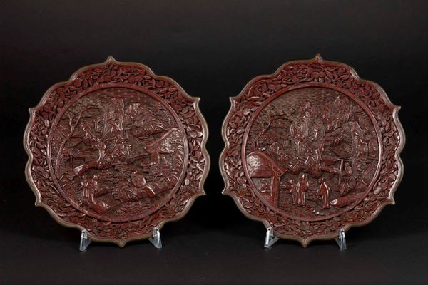 Coppia di piatti in lacca rossa con decoro a rilievo di saggi entro paesaggio, Cina, Dinastia Qing, XIX secolo