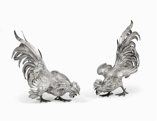 Coppia di grandi galli in argento fuso, sbalzato e cesellato, occhi in pasta vitrea. Germania XX secolo