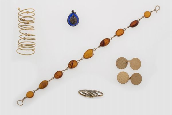Lotto composto da tre anelli a rivière con diamanti, un anello molla, un paio di bottoni da polso, un pendente con smalto blu ed un braccialetto in ambra