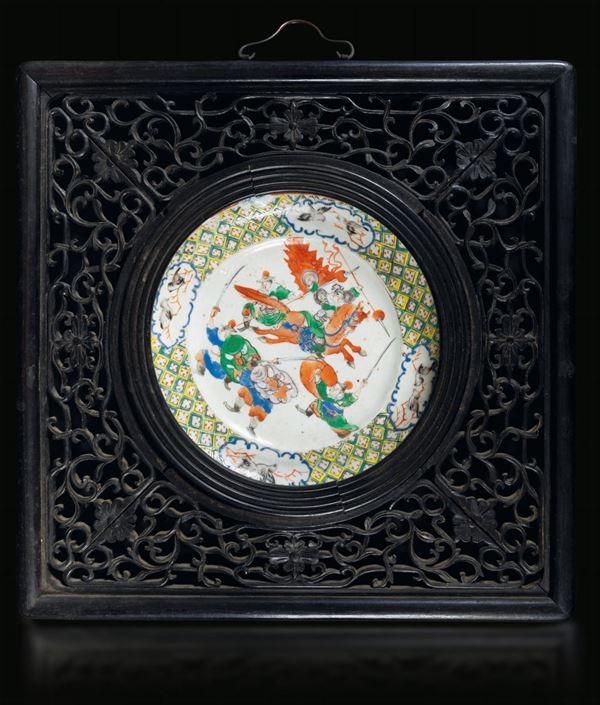 Piatto in porcellana a smalti policromi con figure di guerrieri entro cornice in legno intagliato a motivi vegetali, Cina, Dinastia Qing, epoca Guanxu (1875-1908)
