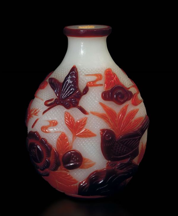 Lotto composto da due snuff bottles in vetro con decoro a cammeo di animali e fiori sui toni del rosso e di figura di drago sui toni del nero, Cina, XX secolo