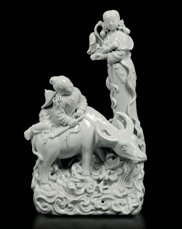 Gruppo in porcellana Blanc de Chine raffigurante fanciulla con scroll e bambino con flauto seduto su bue, Cina, Repubblica, XX secolo