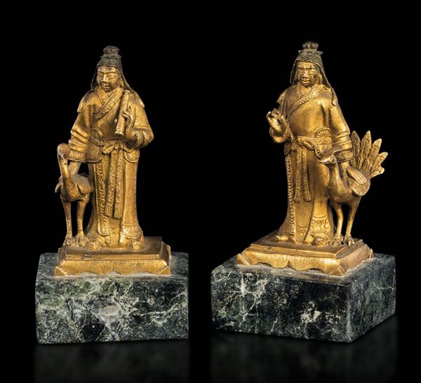 Coppia di sculture in miniatura in bronzo dorato raffiguranti monaci con pavoni montate su basi in marmo, Cina, Dinastia Qing, epoca Qianlong (1736-1796)