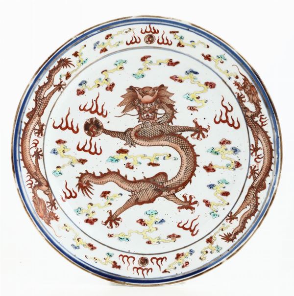 Piatto in porcellana a smalti policromi con decoro di tre draghi tra le nuvole sui toni del rosso, Cina, Dinastia Qing, marchio e del periodo Guangxu (1875-1908)