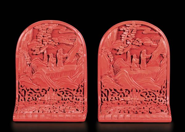 Coppia di fermalibri in lacca rossa con raffigurazioni di saggi e discepoli entro paesaggio e decori floreali, Cina, XX secolo