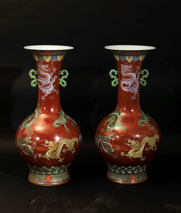 Coppia di grandi vasi a doppia ansa in porcellana a smalti policromi con figure di draghi su fondo rosso, Cina, XX secolo