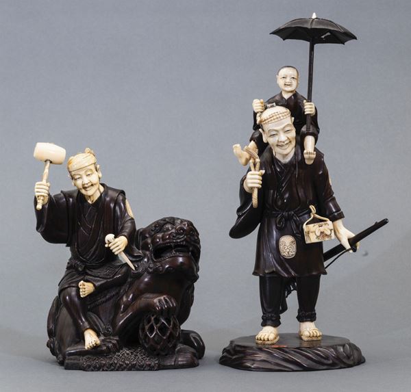 Coppia di sculture diverse raffiguranti personaggio seduto su cane di Pho e uomo con bambino in legno e avorio, Giappone, inizi XX secolo