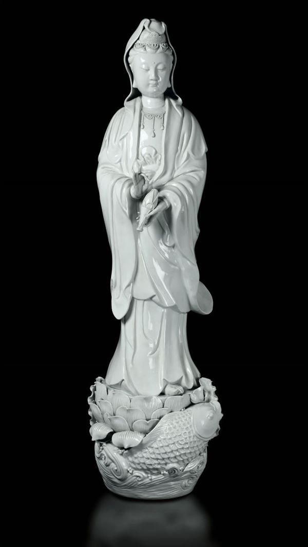 Grande figura di Guanyin eretta su base a foggia di fiore di loto con carpa tra i flutti in porcellana Blanc de Chine, Cina, Dinastia Qing, fine XIX secolo