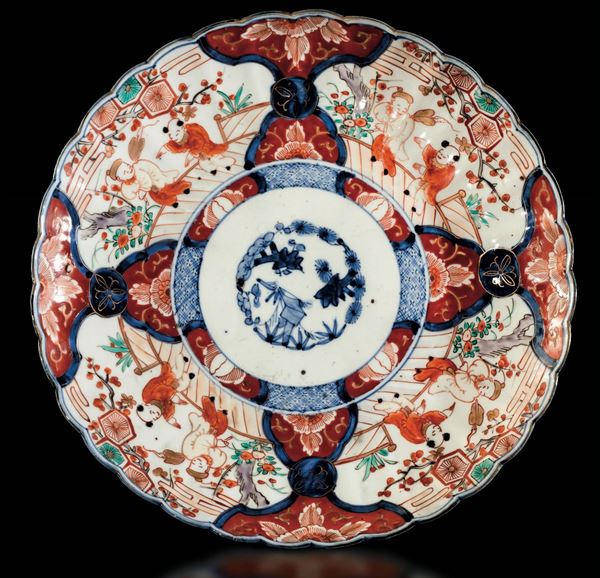 Piatto in porcellana Imari con decori naturalistici e scene di vita comune entro riserve, Giappone, XIX secolo