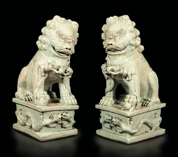 Coppia di grandi leoni in porcellana Blanc de Chine su basi decorate con figure di draghi a rilievo, Cina, XX secolo
