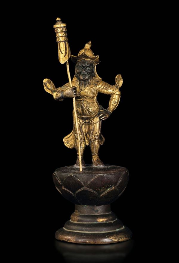 Rara figura di guerriero con stendardo in bronzo dorato poggiante su base a foggia di fiore di loto, Cina, Dinastia Ming, XVII secolo