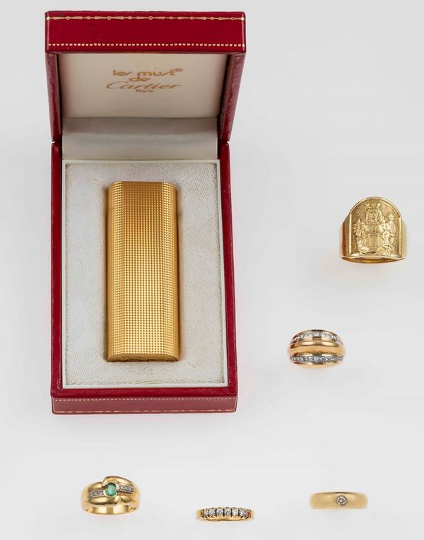 Lotto composto da un accendino Cartier placcato oro e cinque anelli con diamanti ed un piccolo smeraldo