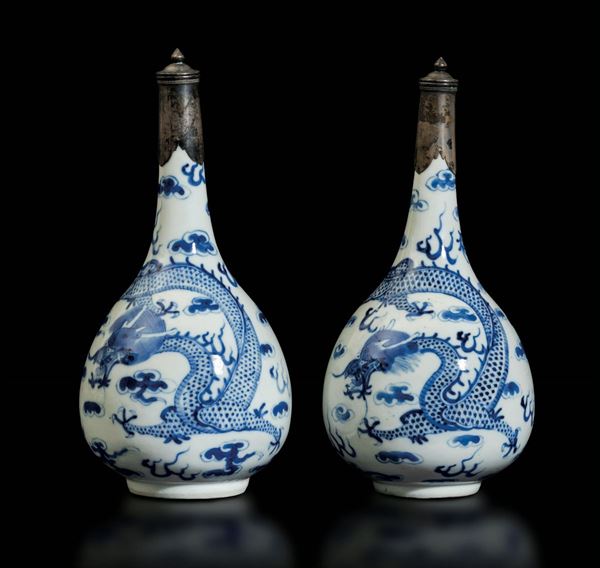 Coppia di vasi a bottiglia in porcellana bianca e blu con decoro di draghi tra le nuvole e terminali in argento, Cina, Dinastia Qing, epoca Kangxi (1662-1722)