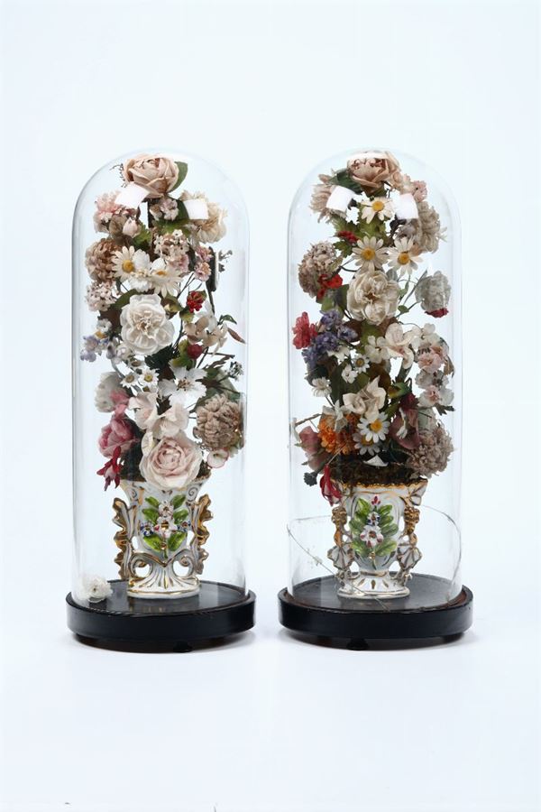 Coppia di vasi in porcellana con fiori in tessuto, entro campane in vetro
