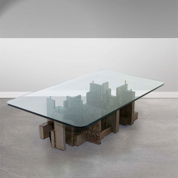 Tavolo basso con struttura in metallo lavorato e piano in vetro molato di forte spessore.