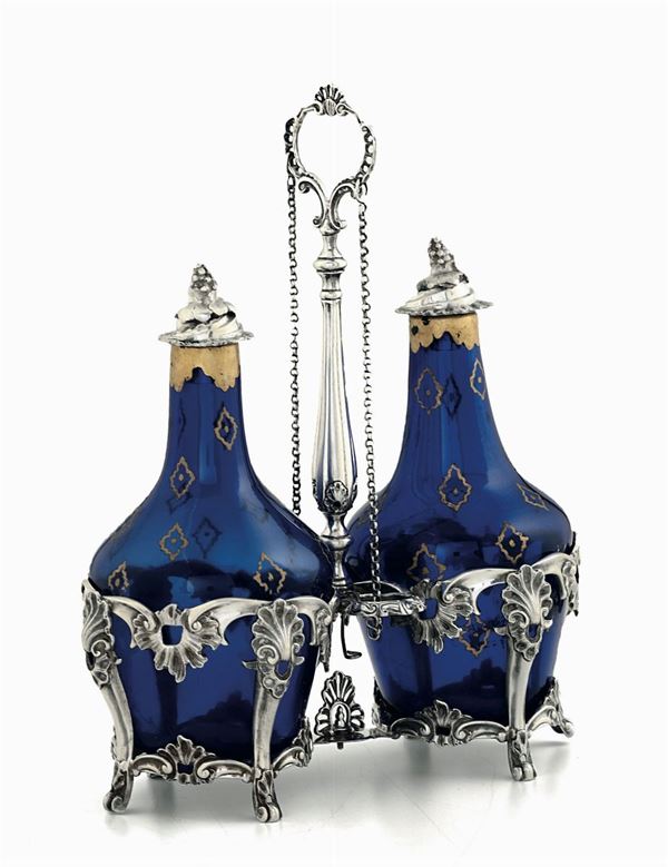 Oliera in argento fuso, sbalzato e cesellato, con ampolle in vetro soffiato blu e dorato. Manifattura europea del XIX-XX secolo (marchi di titolo e dell’argentiere non identificati)