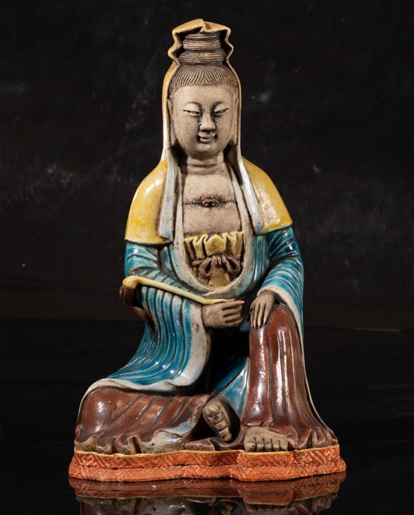 Figura di Guanyin con strumento rituale seduta in porcellana a smalti policromi, Cina, XX secolo