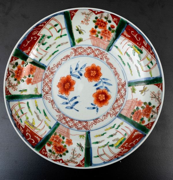 Piatto in porcellana a smalti policromi con scene naturalistiche entro riserve e decori floreali, Giappone, XIX secolo