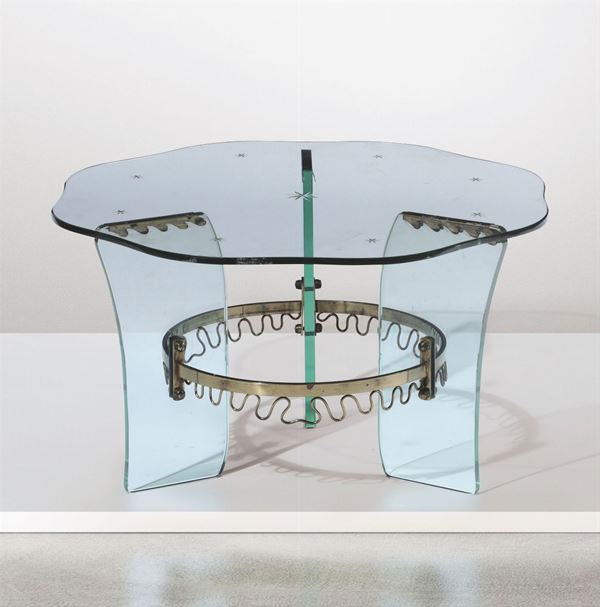 Tavolo basso con struttura in cristallo molato, particolari in ottone e piano in vetro serigrafato.