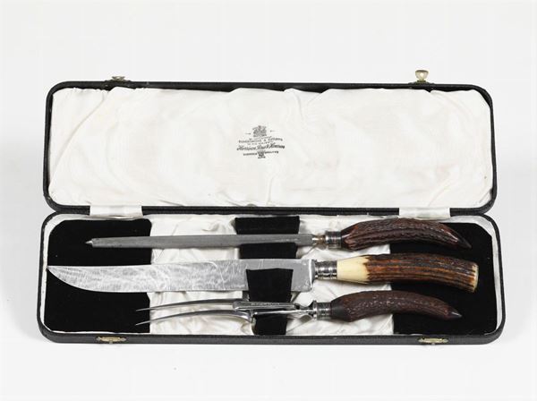 Set con coltello, forchetta e affila coltello in metallo e manico in corno, entro custodia. Inghilterra XIX-XX secolo