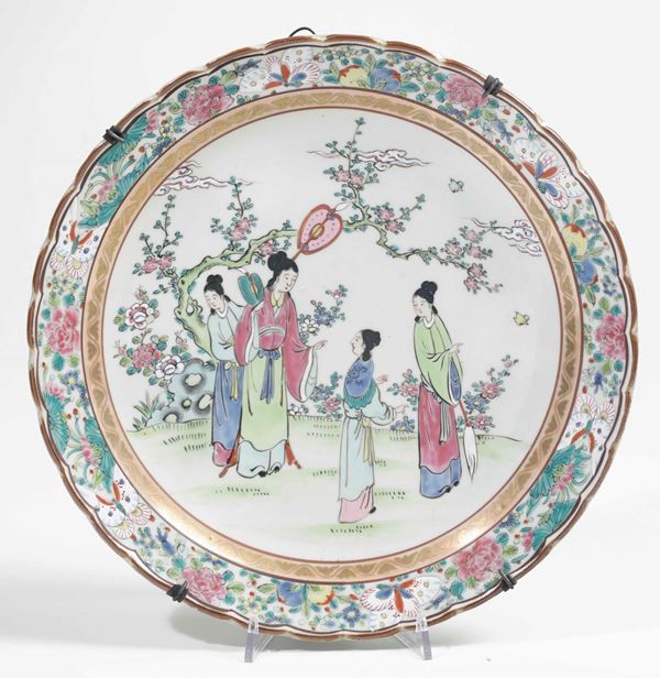 Piatto in porcellana a smalti policromi sui toni della Famiglia Rosa con figure di cortigiane entro paesaggio e decori floreali, Cina, XX secolo