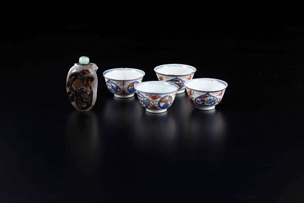 Lotto composto da quattro piccole tazzine in porcellana Imari e una snuff bottle in agata muschiata con figura di draghetto a rilievo, Cina, XX secolo