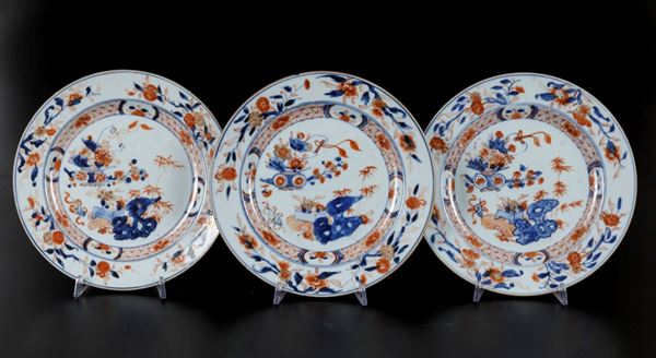 Tre piatti in porcellana Imari con soggetto naturalistico centrale e decori floreali, Cina, Dinastia Qing, epoca angxi (1662-1722)