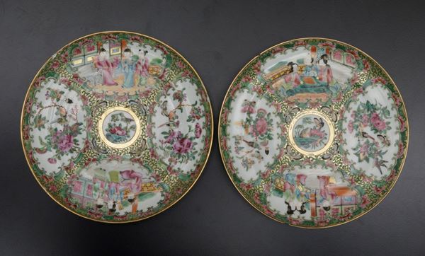 Coppia di piatti in porcellana Canton Famiglia Rosa raffiguranti scene di vita comune entro riserve e decori floreali, Cina, Dinastia Qing, XIX secolo
