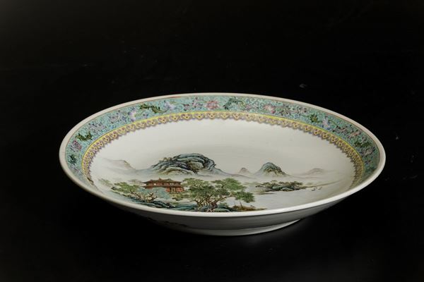 Piatto in porcellana a smalti policromi con paesaggio e decori floreali, Cina, XX secolo