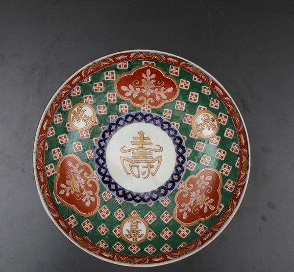 Piatto in porcellana Imari con simboli taoisti e decori floreali entro riserve, Giappone, periodo Meiji (1868-1912)