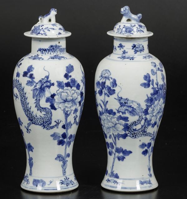 Coppia di piccole potiches in porcellana bianca e blu con draghi, decori floreali e presa a foggia di leoncino, Cina, Dinastia Qing, XIX secolo
