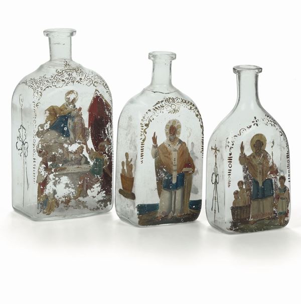 Gruppo di tre bottiglie per la manna in vetro soffiato incolore decorate con immagini di San Nicola e dei suoi miracoli. Italia XVIII secolo