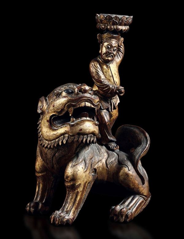 Lume da tavolo costituito da scultura di saggio che cavalca un cane drago in legno intagliato e dorato. Cina, fine XIX secolo