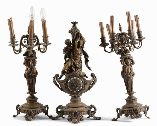 Trittico da camino in bronzo brunito composta da due candelabri e un orologio con figura femminile
