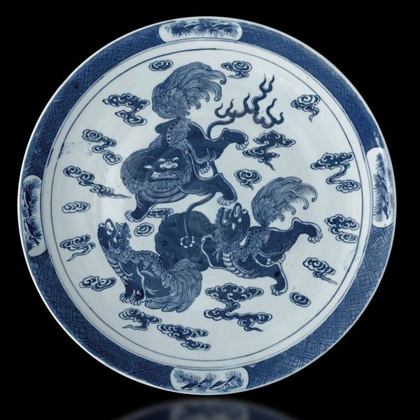 Piatto in porcellana bianca e blu raffigurante cani di Pho e soggetti naturalistici entro riserve, Cina, Dinastia Qing, epoca Daoguang (1821-1850)