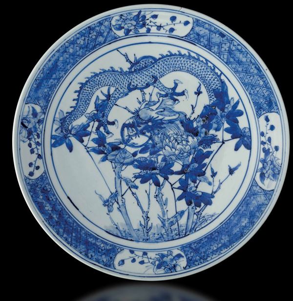 Piatto in porcellana bianca e blu con figura di drago, rami in fiore e soggetti naturalistici entro riserve, Cina, Dinastia Qing, XIX secolo