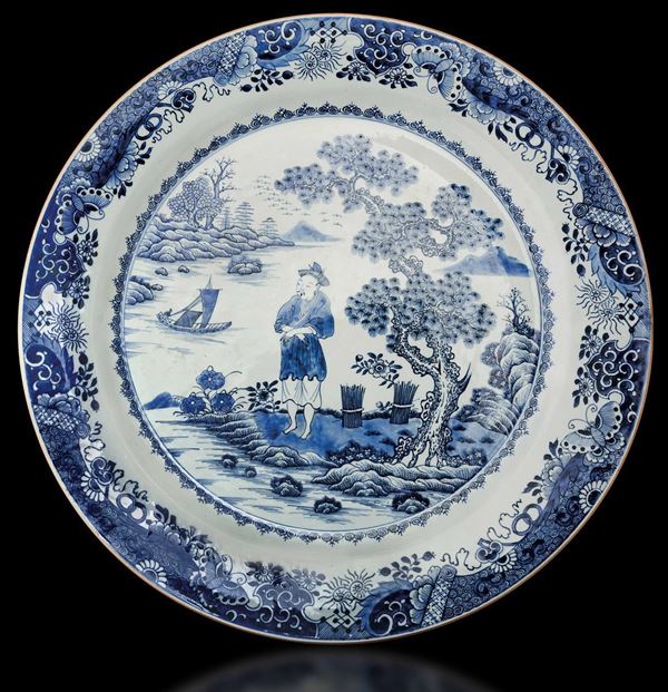 Grande piatto in porcellana bianca e blu con figura di contadino entro paesaggio e decori floreali, Cina, Dinastia Qing, epoca Qianlong (1736-1796)