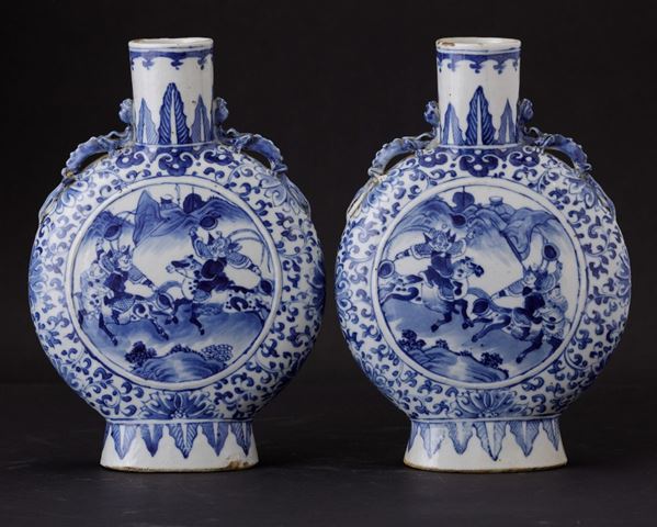 Coppia di fiasche in porcellana bianca e blu con scene di vita comune entro riserve e figure di draghetto a rilievo, Cina, Dinastia Qing, epoca Guangxu (1875-1908)