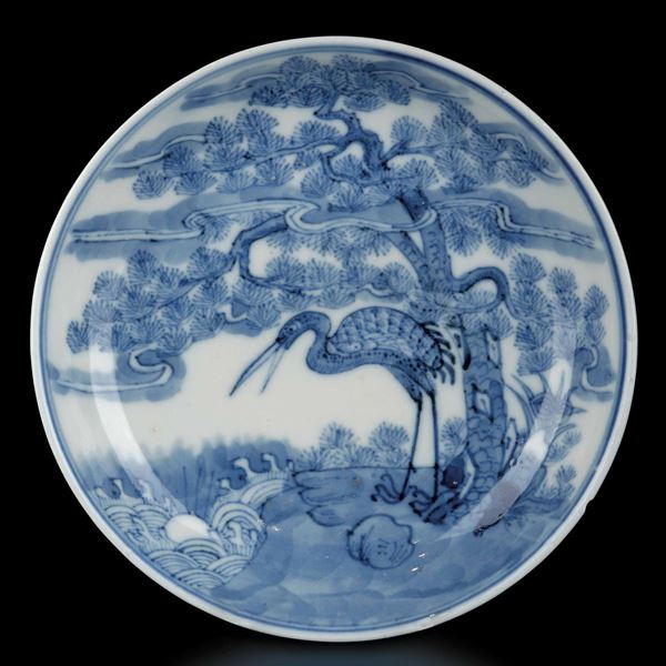 Piattino in porcellana bianca e blu con figura di airone entro paesaggio, Cina, Dinastia Qing, marca e del periodo Guangxu (1875-1908)