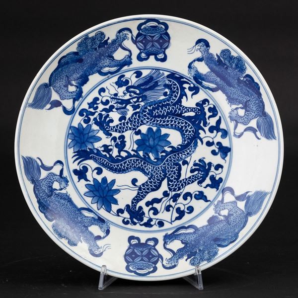 Piatto in porcellana bianca e blu con figura di drago centrale e cani di Pho, Cina, XX secolo