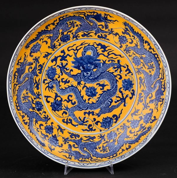 Piatto in porcellana  con decoro a cinque draghi e fiori di loto su fondo giallo, Cina, XX secolo