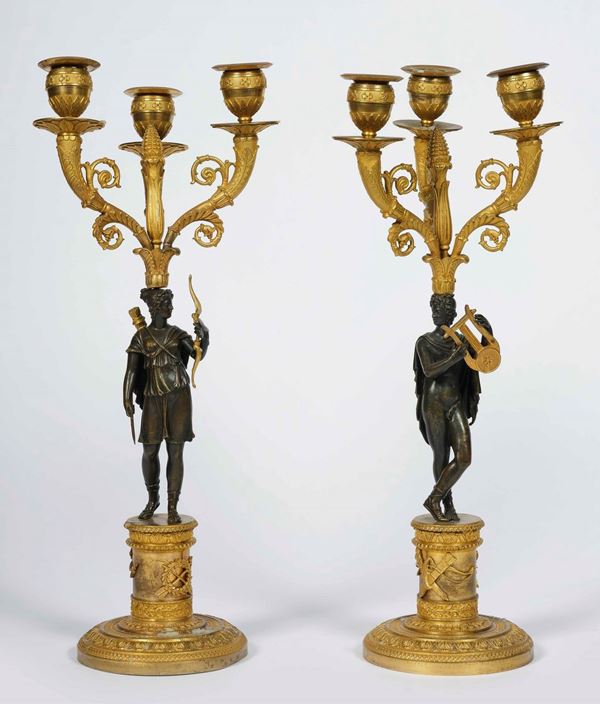 Coppia di candelabri a tre fiamme in bronzo cesellato, dorato e patinato. Francia inizio XIX secolo